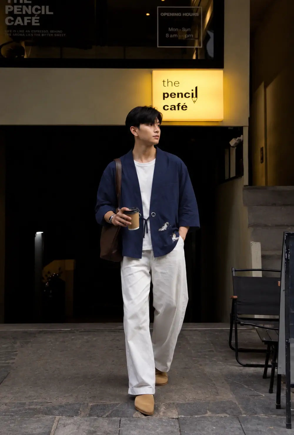 Chemise kimono homme bleue style japonais portée fermée sur un pantalon blanc devant un café