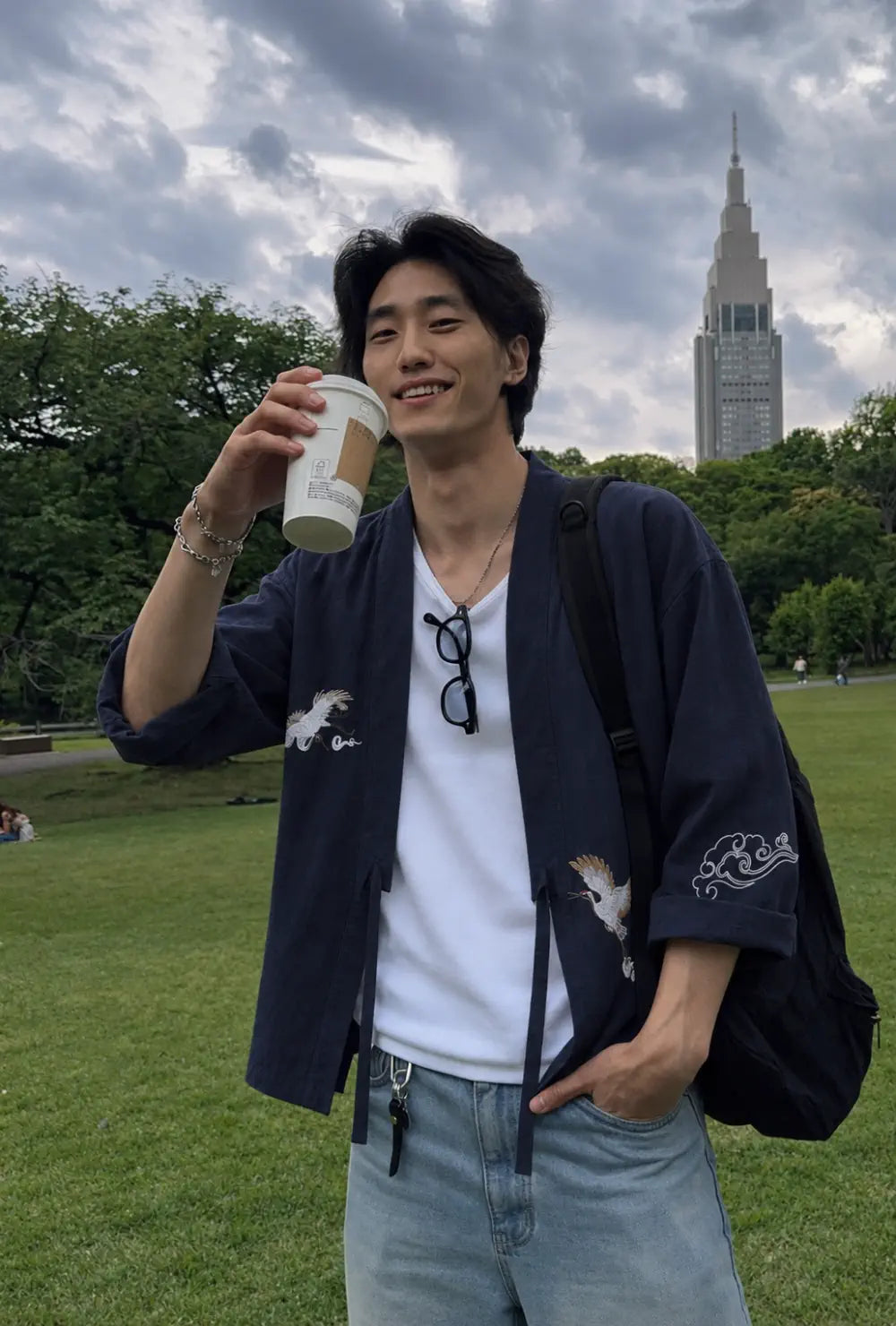Haori homme bleu en coton à motif grues porté ouvert sur un t-shirt blanc et un jean dans un parc