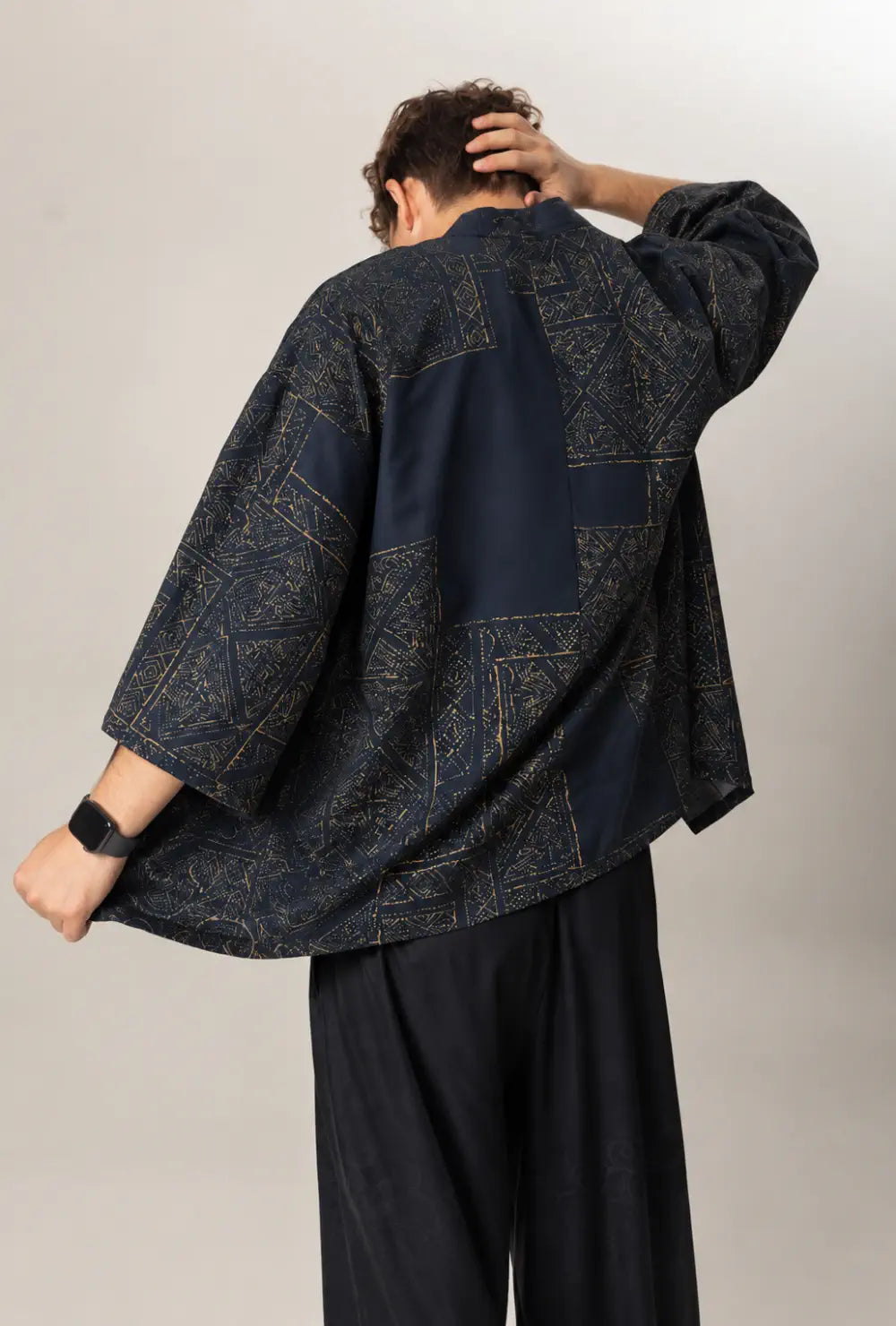 Haori homme bleu marine en coton à motifs dorés porté ouvert vu de dos devant un fond gris clair