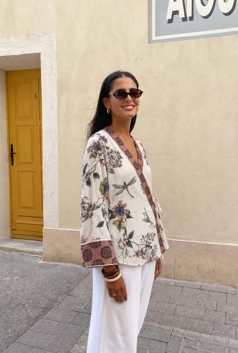 Kimono court femme blanc fleuri de style japonais porté sur un jean clair, un café à la main en ville