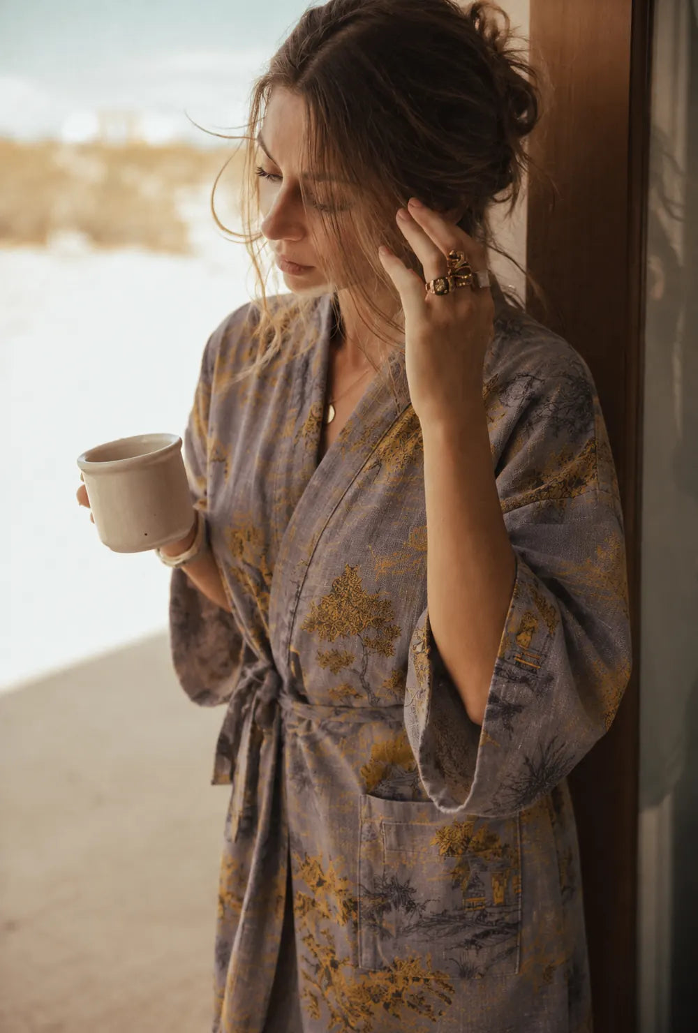 peignoir kimono gris porté à la fenêtre avec une tasse