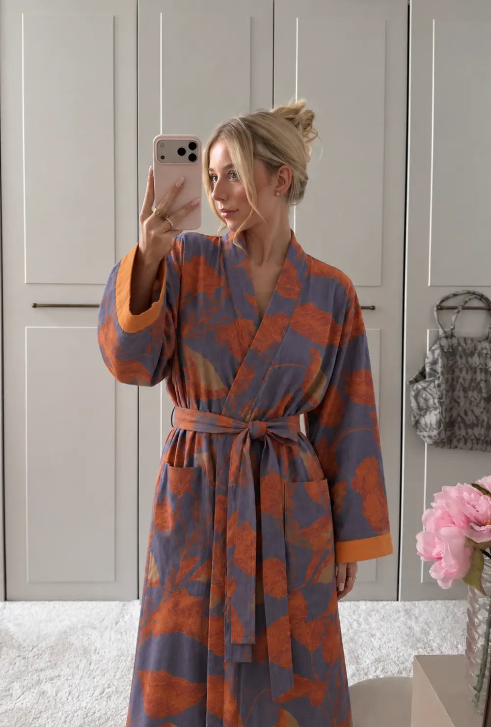 Peignoir kimono femme orange et bleu en coton porté ceinturé devant un dressing blanc