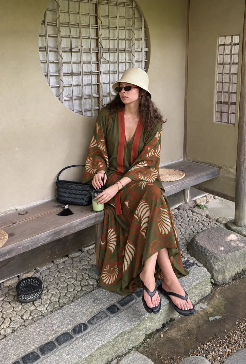 Robe japonaise longue femme verte et rouge chic portée avec un bob assise sur un banc dans un jardin japonais