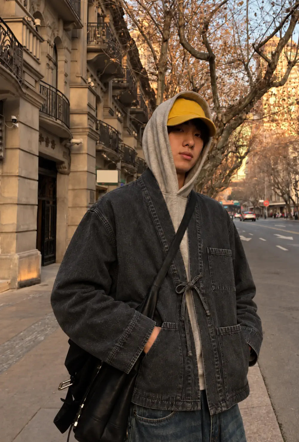 Veste kimono denim homme noire en coton portée nouée sur un sweat à capuche gris dans une rue