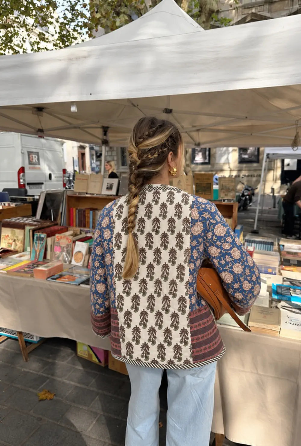 Veste kimono femme bleue matelassée chic portée de dos sur un jean clair devant un stand de livres