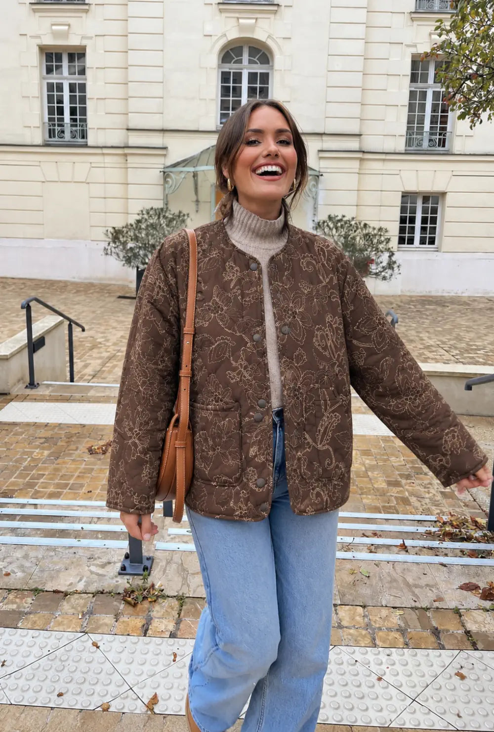 Veste kimono femme marron matelassée en coton fleuri portée sur un col roulé beige et un jean dans une cour