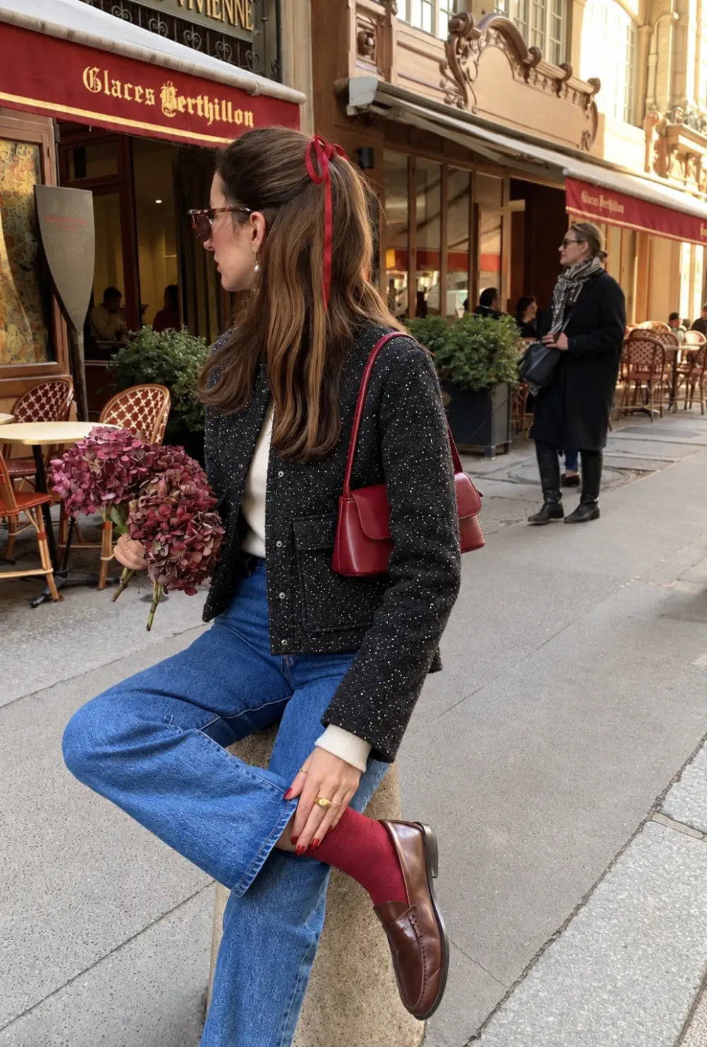 Veste kimono femme noire à paillettes portée sur un jean bleu devant une terrasse de café en ville