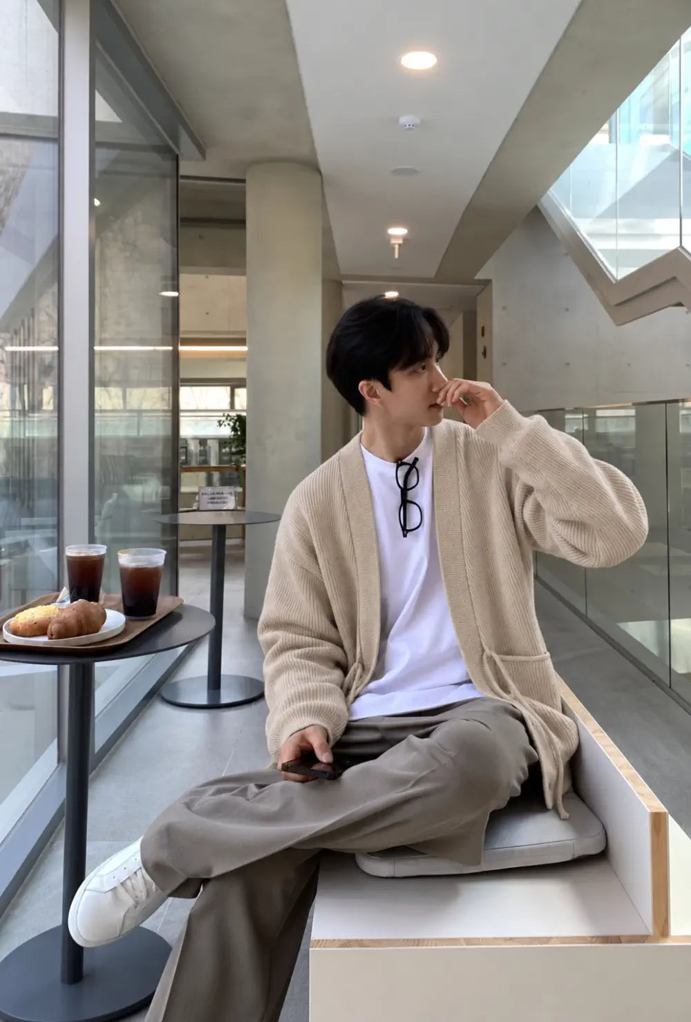 Veste kimono homme beige style cardigan portée ouverte sur un t-shirt blanc dans un café moderne